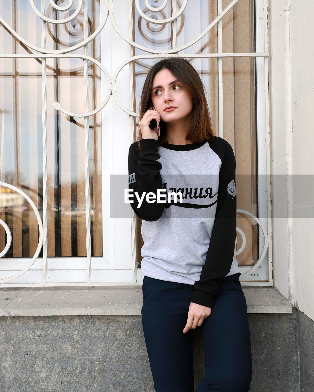 Young woman talking on phone while standing by window