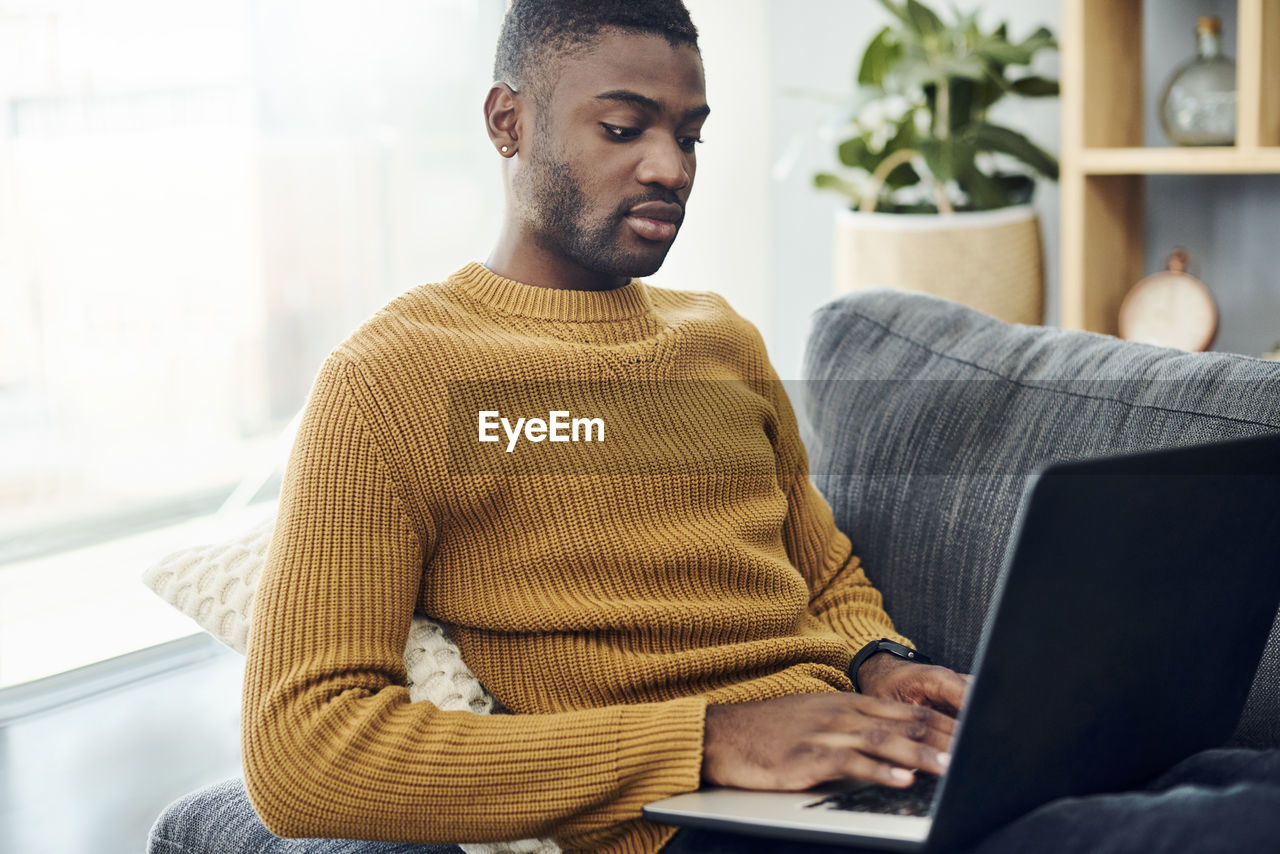 Young man using mobile phone at home