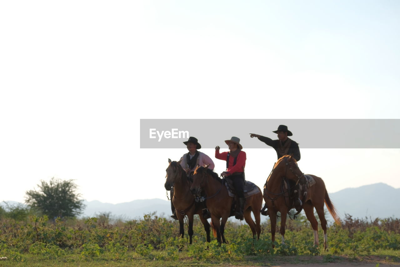 PEOPLE RIDING HORSES ON FIELD