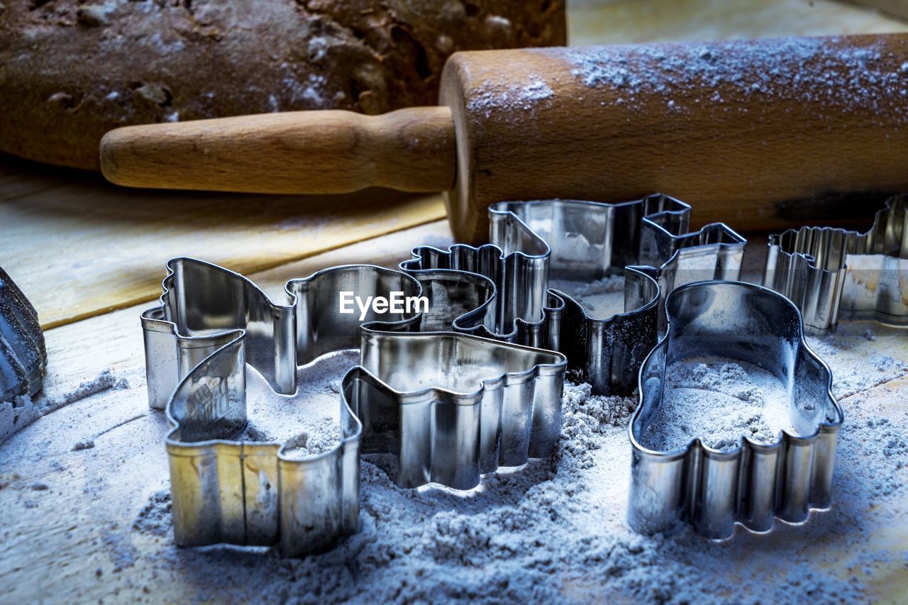 Close-up of pastry cutters with flour and rolling pin on table