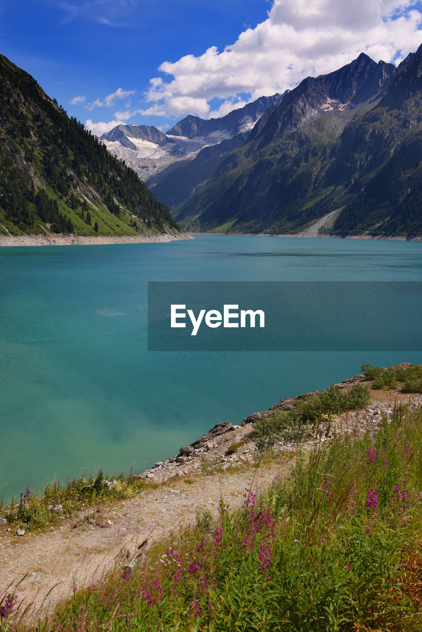 scenic view of lake by mountains against sky