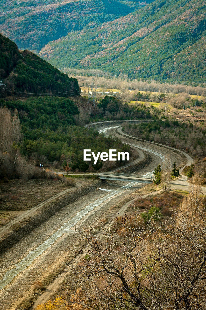 HIGH ANGLE VIEW OF ROAD AMIDST TREES AND MOUNTAINS