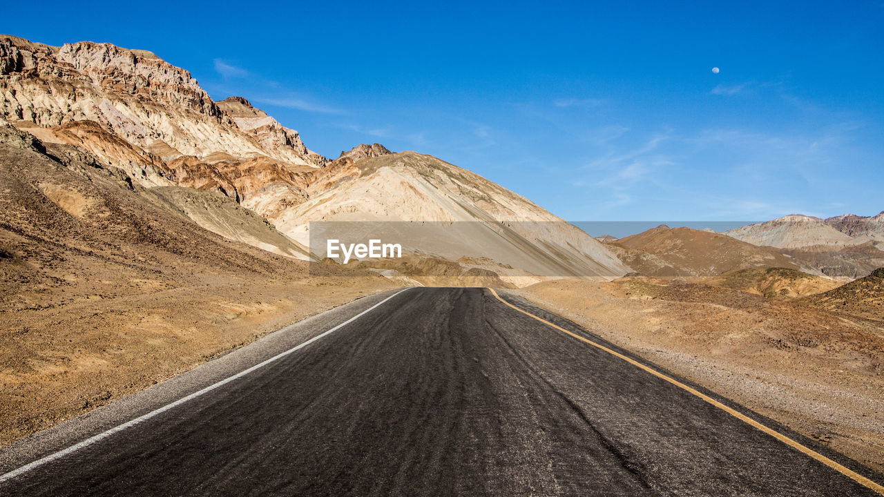 Road leading towards mountains against sky