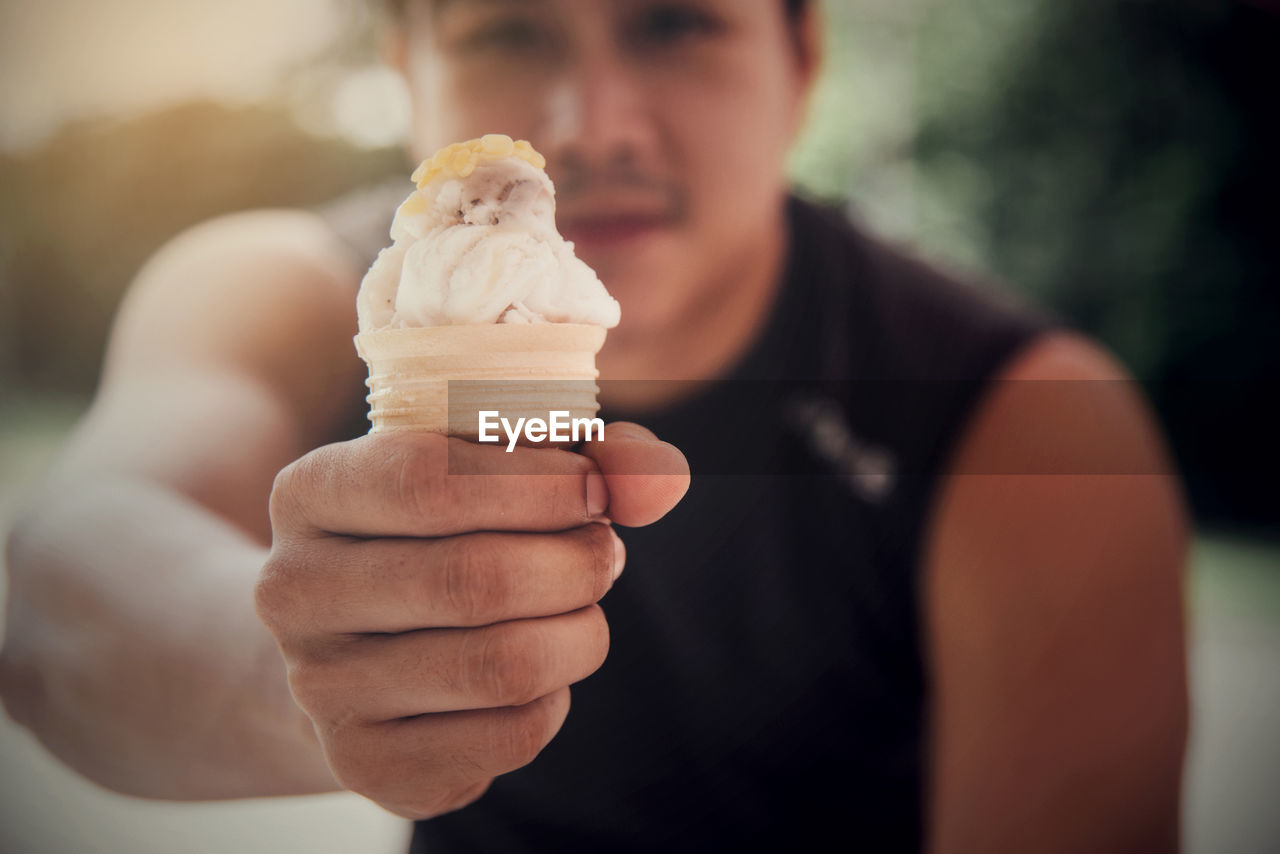 Midsection of man holding ice cream outdoors