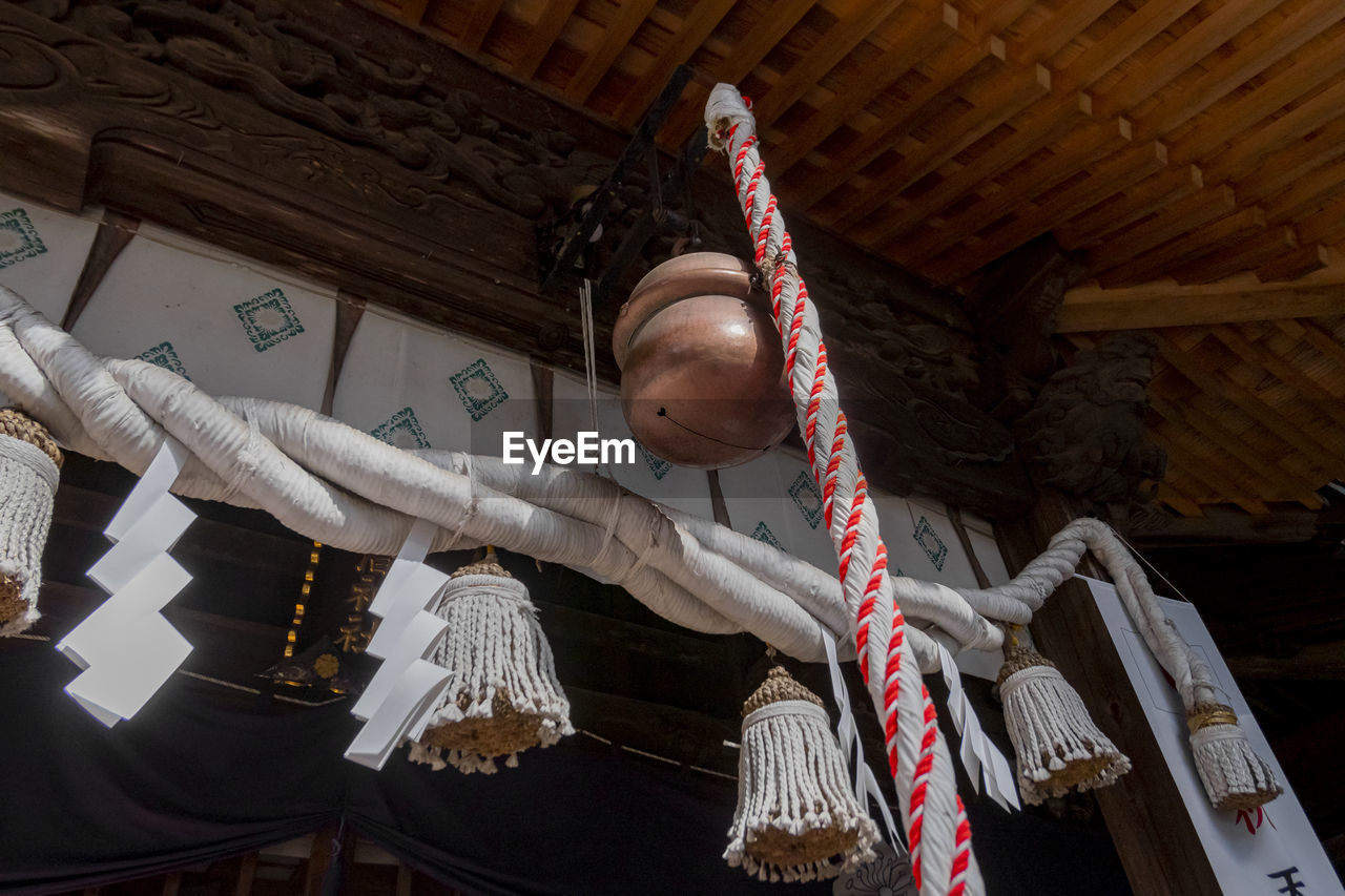 Low angle view of mini bells hanging on rope against building