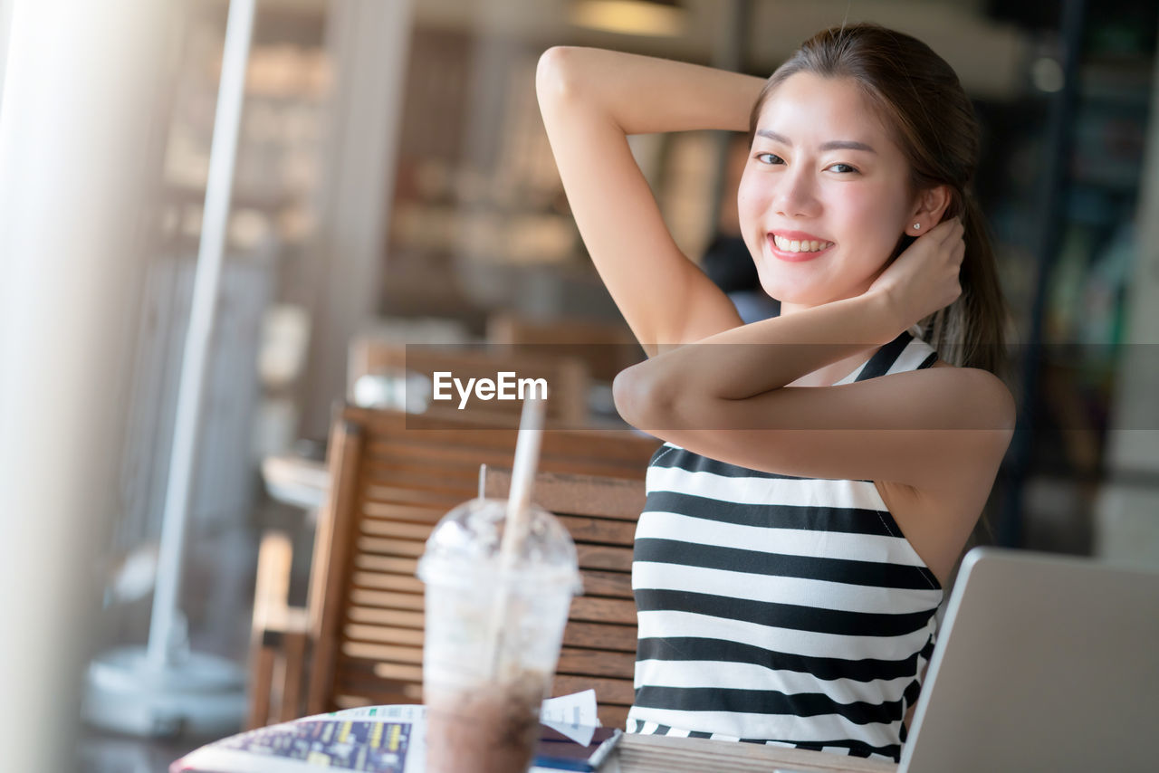 PORTRAIT OF SMILING WOMAN HOLDING ICE CREAM