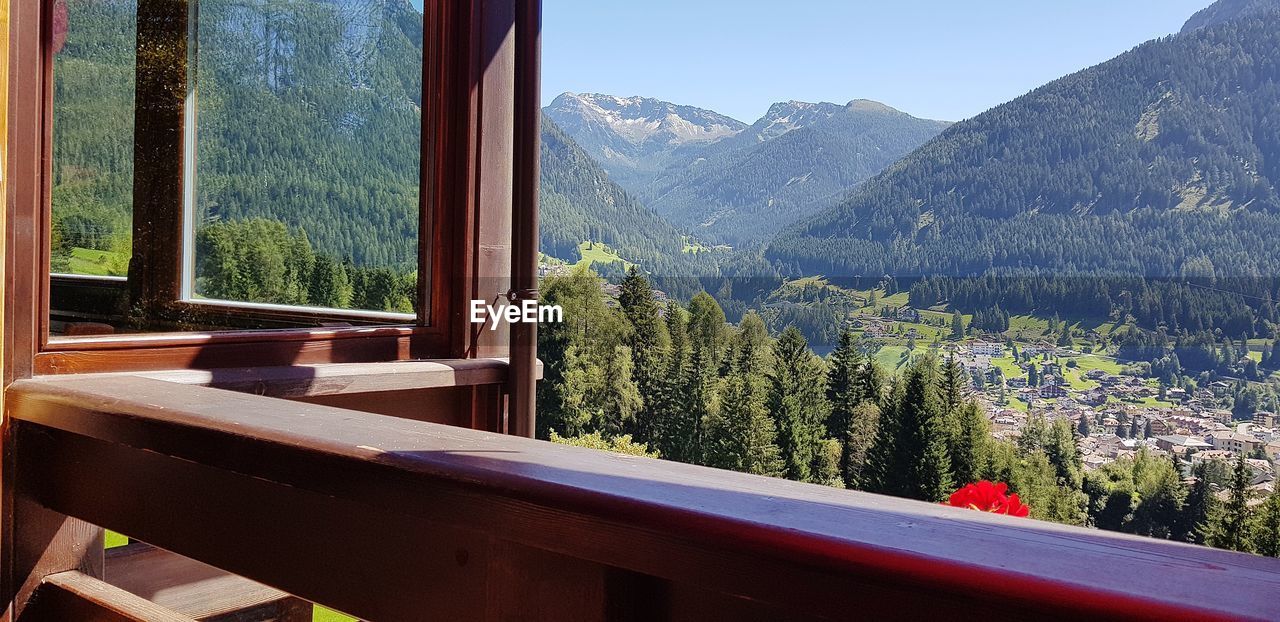 PLANTS BY WINDOW AGAINST MOUNTAINS