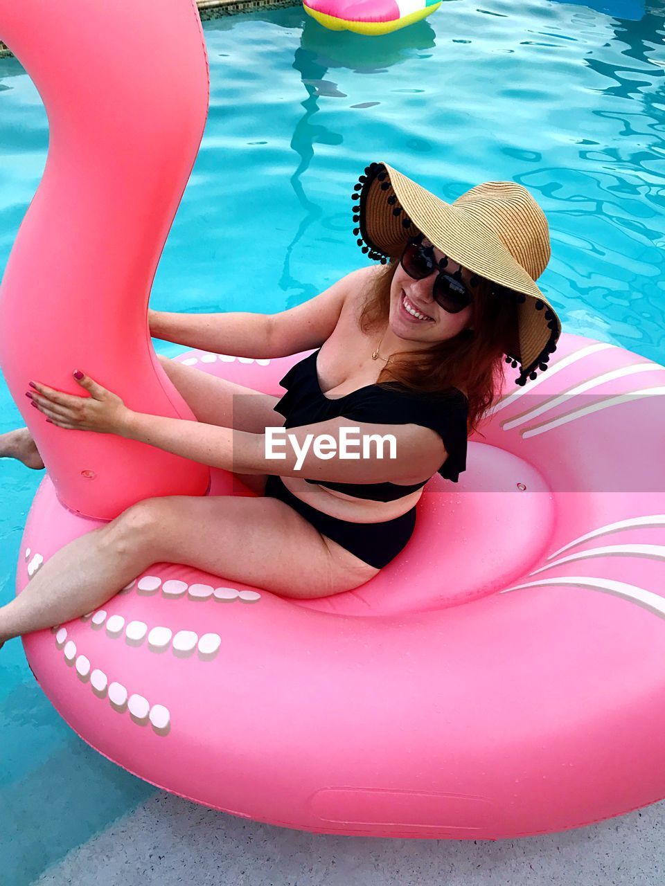 Portrait of happy woman sitting on pool raft in swimming pool