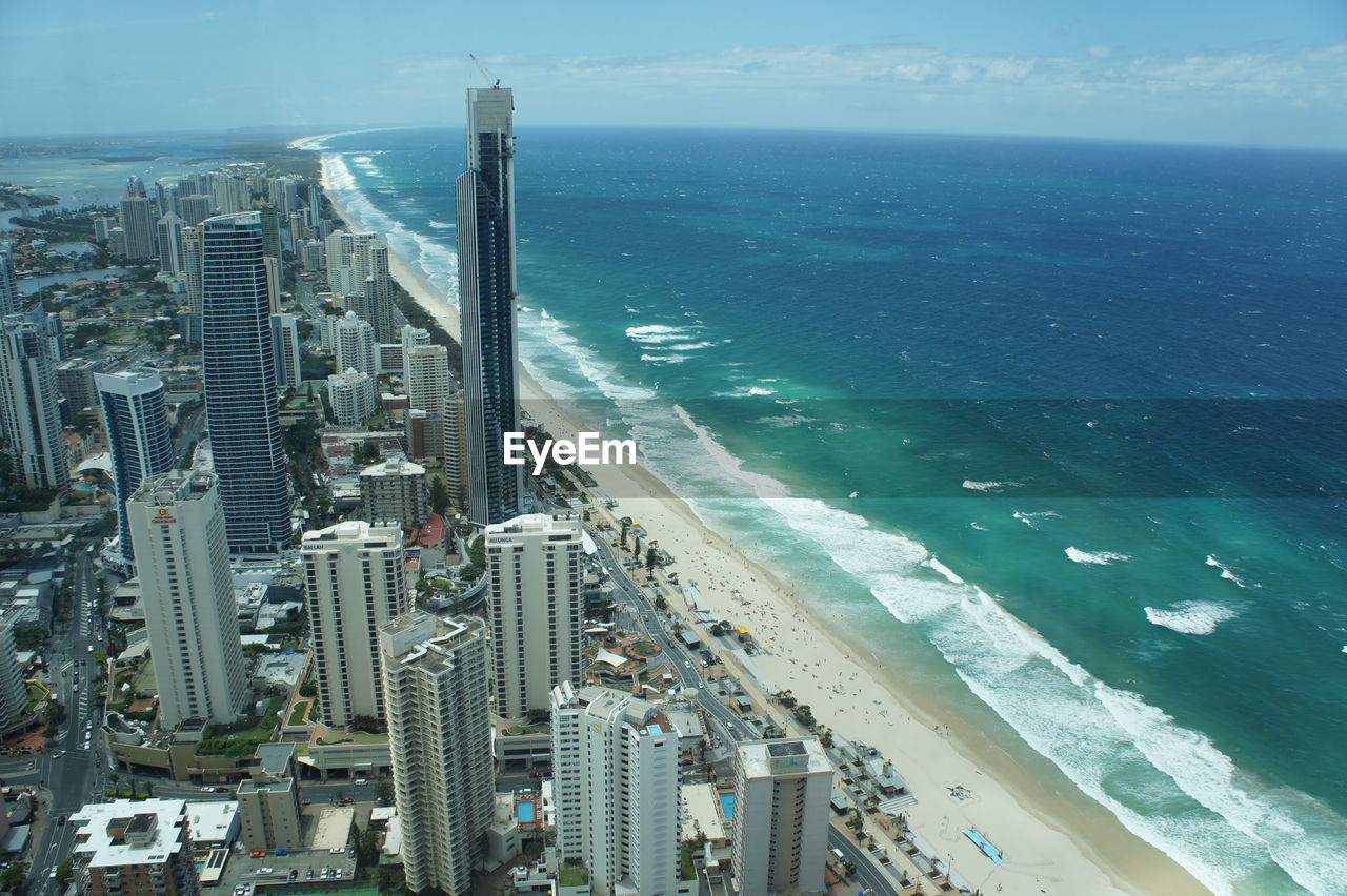 HIGH ANGLE VIEW OF SEA BY CITYSCAPE AGAINST SKY