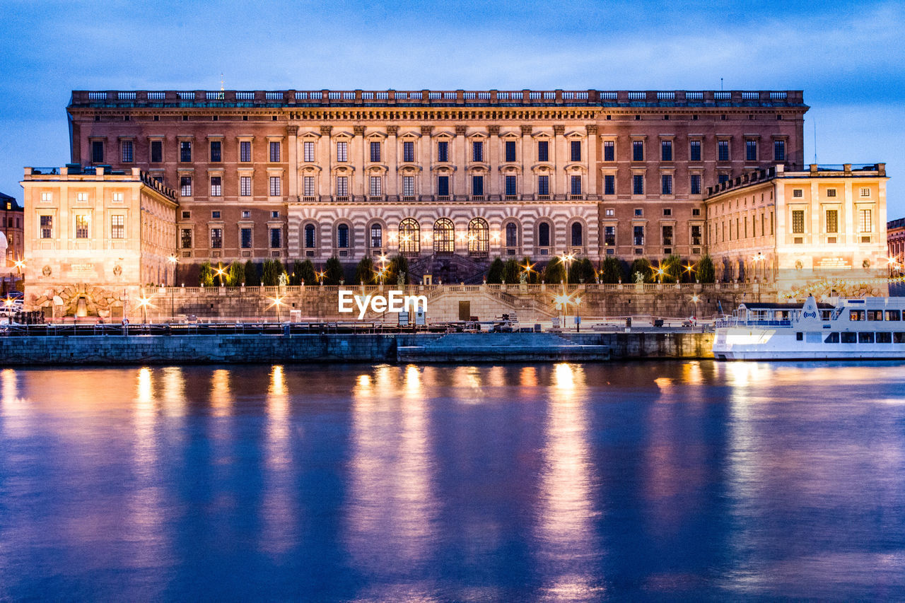 Illuminated palace by river in told town at dusk