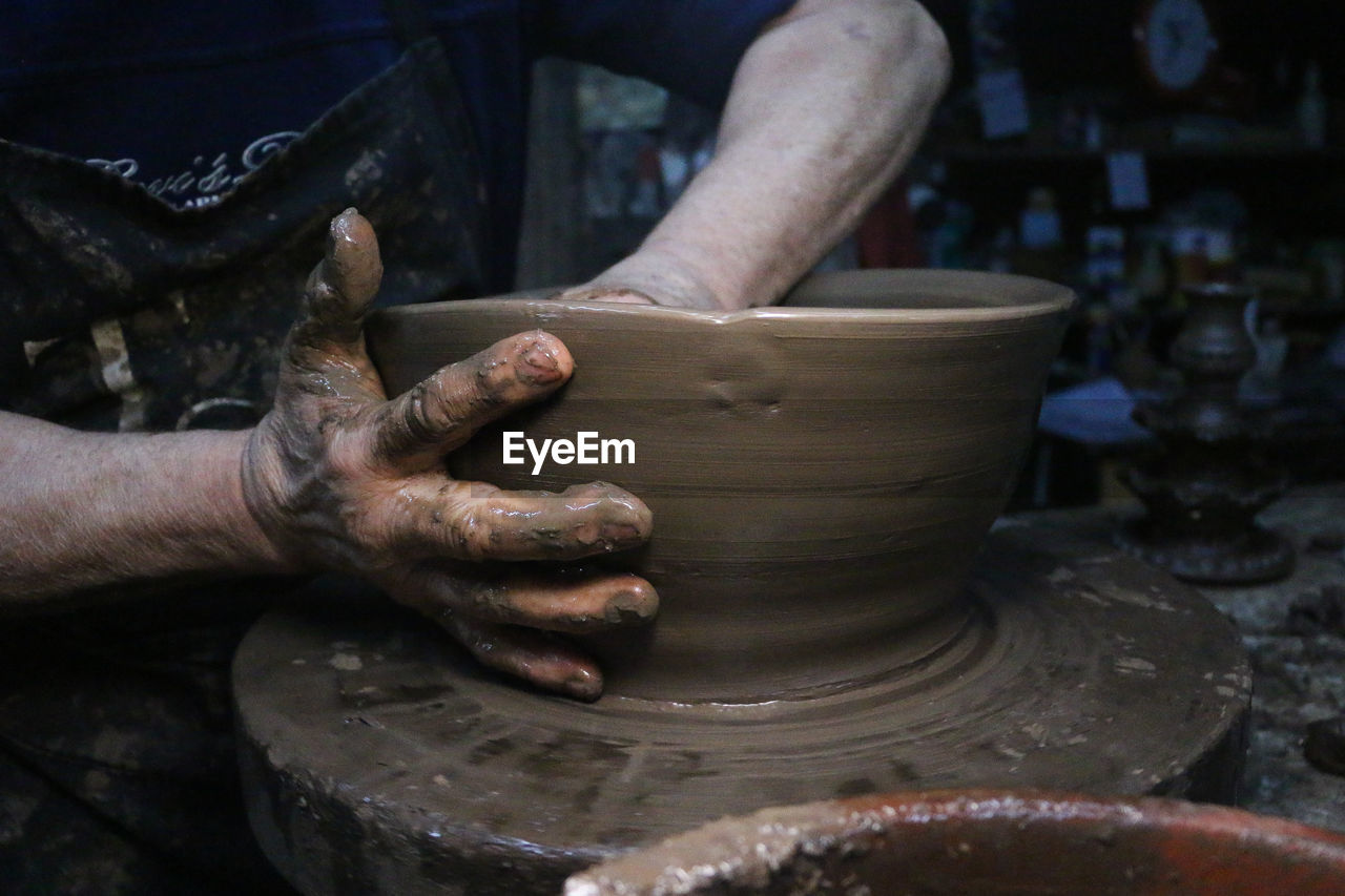 Midsection of man making pottery in workshop