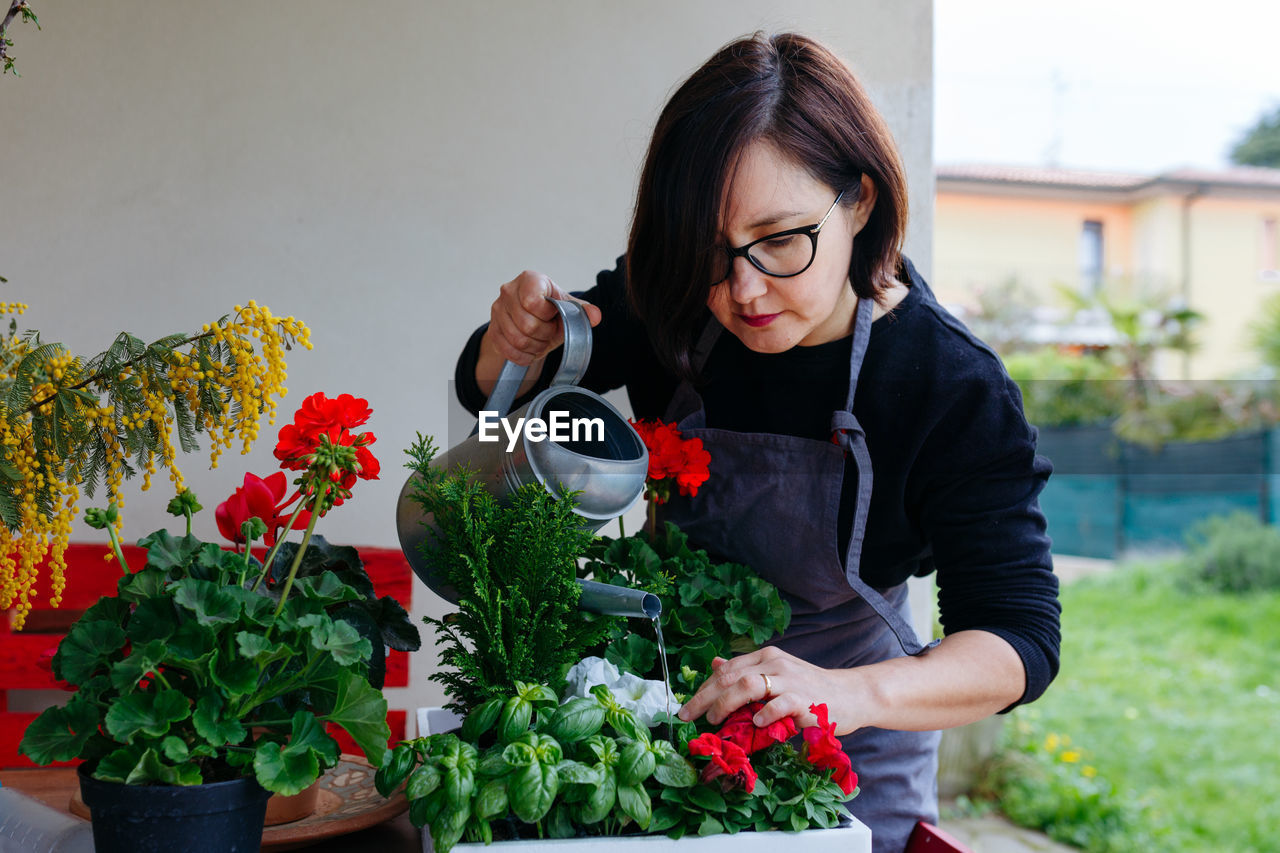Dark hair woman watering potted plants outdoors
