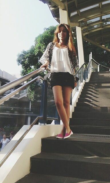FULL LENGTH OF YOUNG WOMAN STANDING ON RAILING