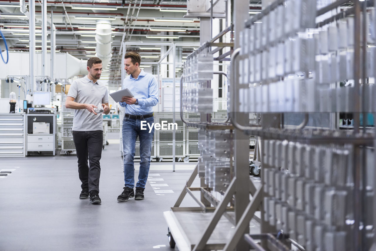 Two men with tablet talking about a product in factory shop floor