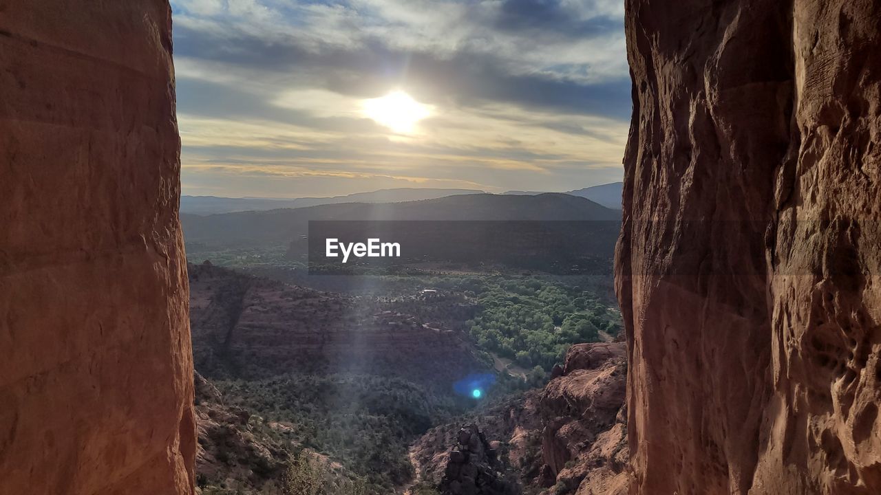 sky, scenics - nature, nature, cloud, environment, mountain, beauty in nature, landscape, rock, sun, travel, sunlight, sunset, travel destinations, tranquility, no people, outdoors, land, lens flare, canyon, sunbeam, mountain range, terrain, tranquil scene, non-urban scene, cliff, architecture, tourism, rock formation, panoramic, water, idyllic, horizon