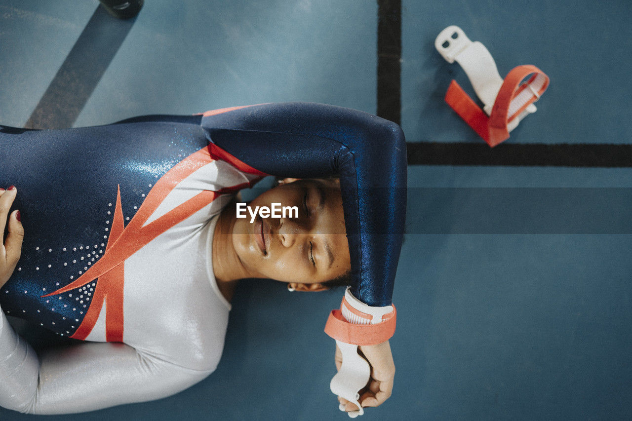 Directly above shot of female teenage athlete with eyes closed resting on floor