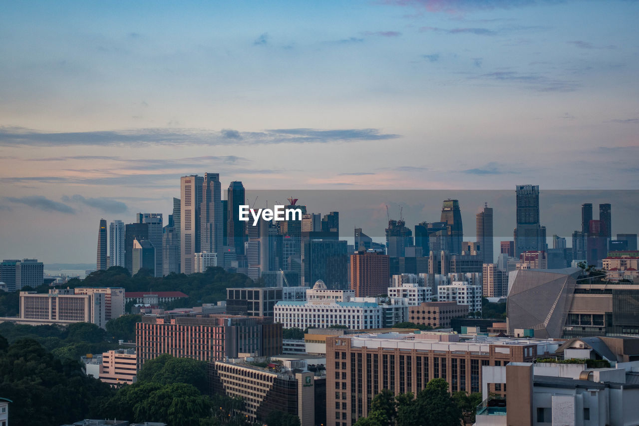 Modern cityscape against sky during sunset