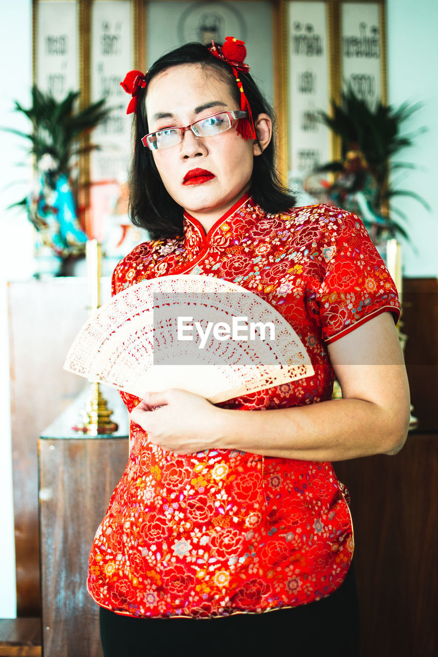 one person, red, adult, women, portrait, clothing, fashion, young adult, glasses, looking at camera, eyeglasses, costume, female, standing, retro styled, dress, three quarter length, person, emotion, lifestyles, indoors, waist up, human face, pattern, elegance