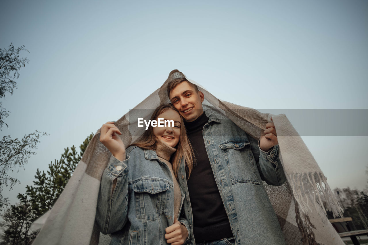 A young couple is covered with a plaid in the form of a house roof. house concept