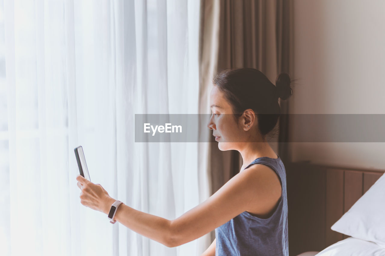 Side view of young woman using mobile phone at home