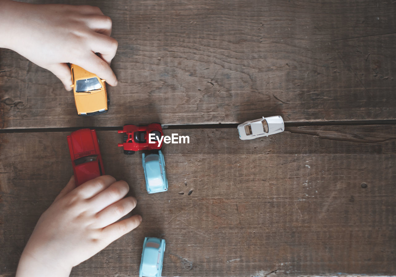 Cropped hands of person playing with toy cars on table