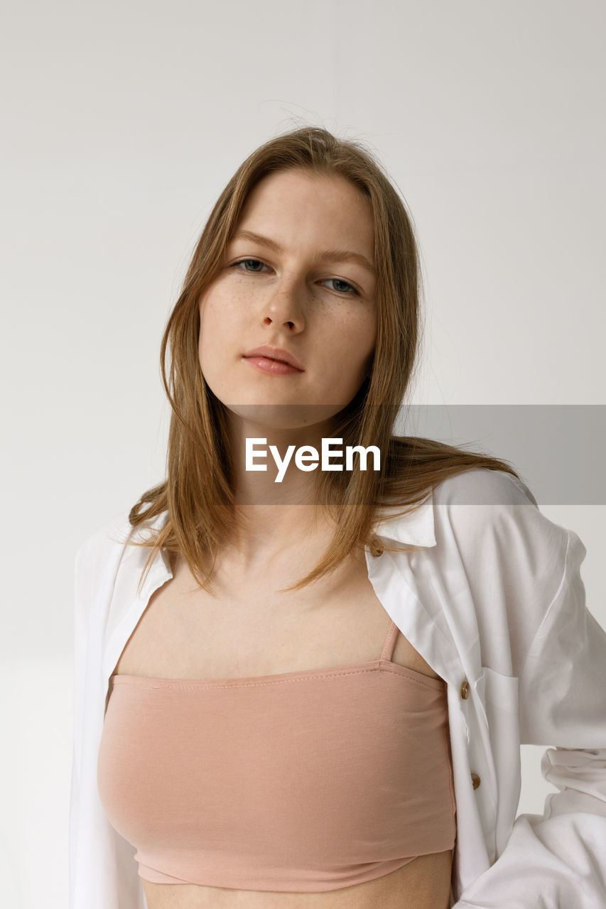 PORTRAIT OF A BEAUTIFUL YOUNG WOMAN AGAINST WHITE BACKGROUND