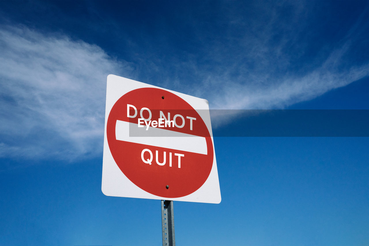 Low angle view of message on pole against blue sky