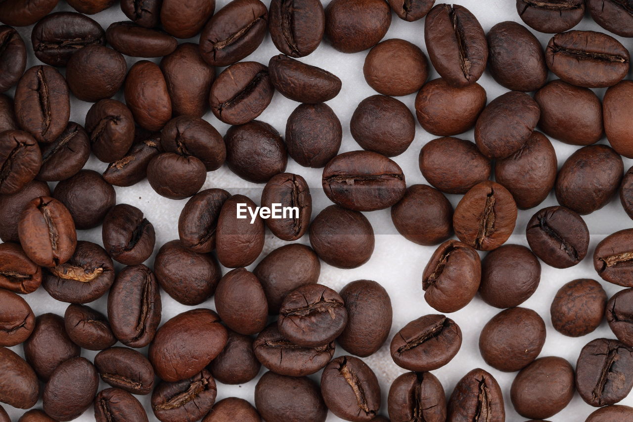 Coffee beans are scattered on a white table. photo of freshly roasted coffee close-up of high