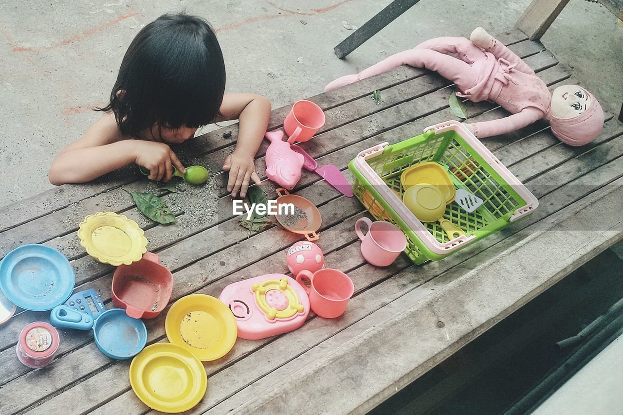 High angle view of girl playing with toys on wooden table at yard