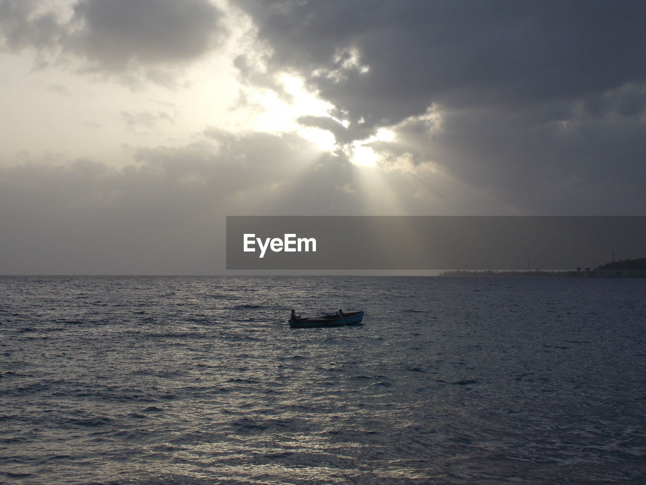 Silhouette boat amidst sea against cloudy sky