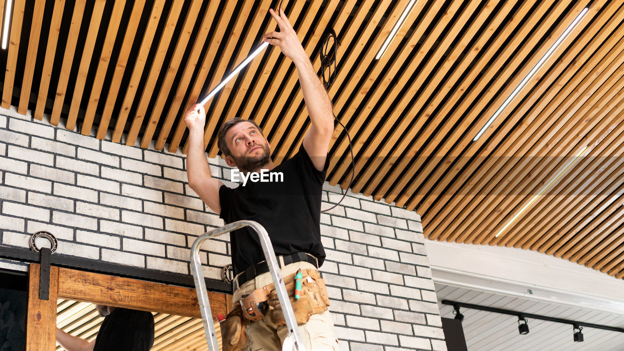 Low angle view of man repairing ceiling