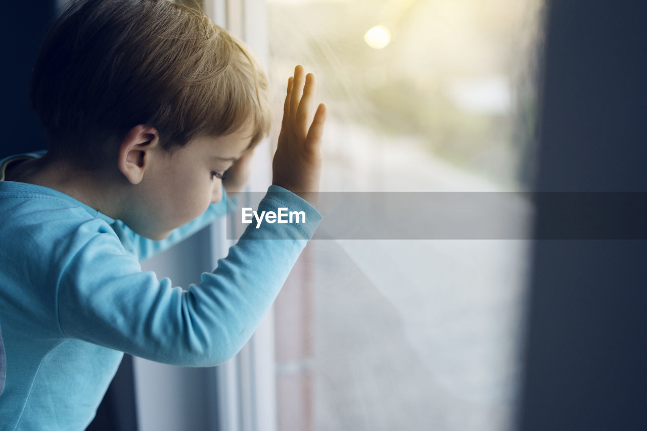 Close-up of boy looking through glass window