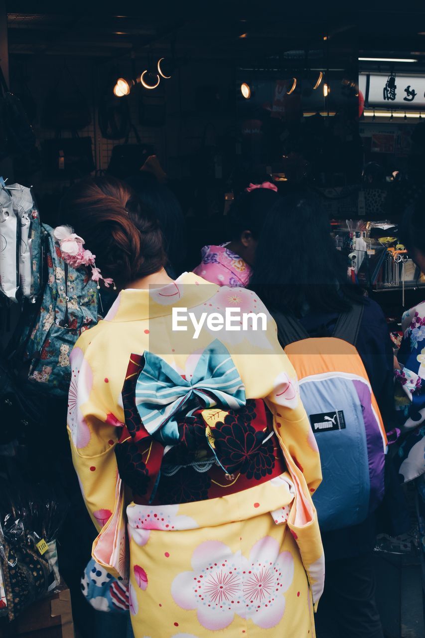 REAR VIEW OF WOMAN STANDING AT MARKET