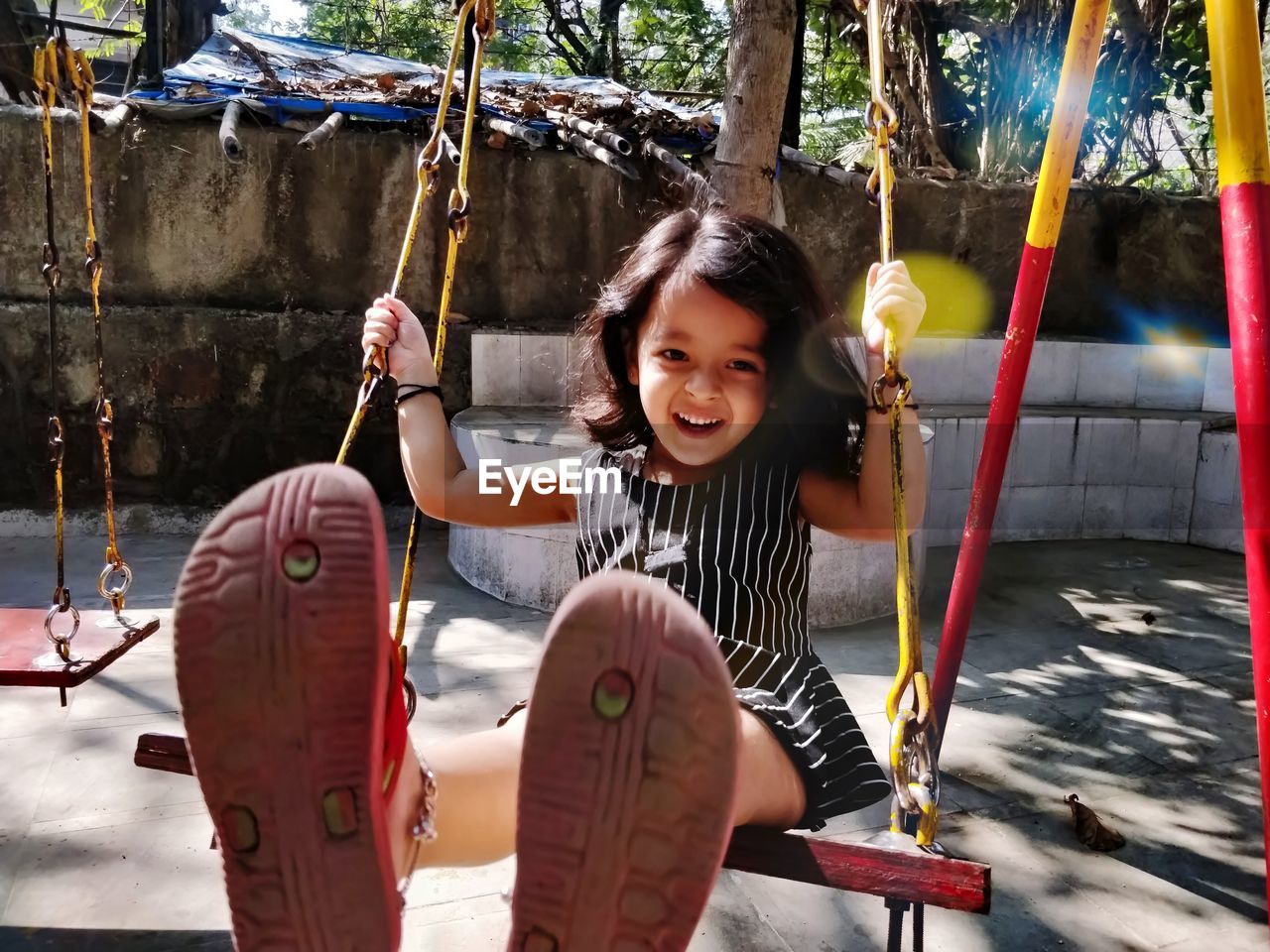 Portrait of smiling girl on swing in playground