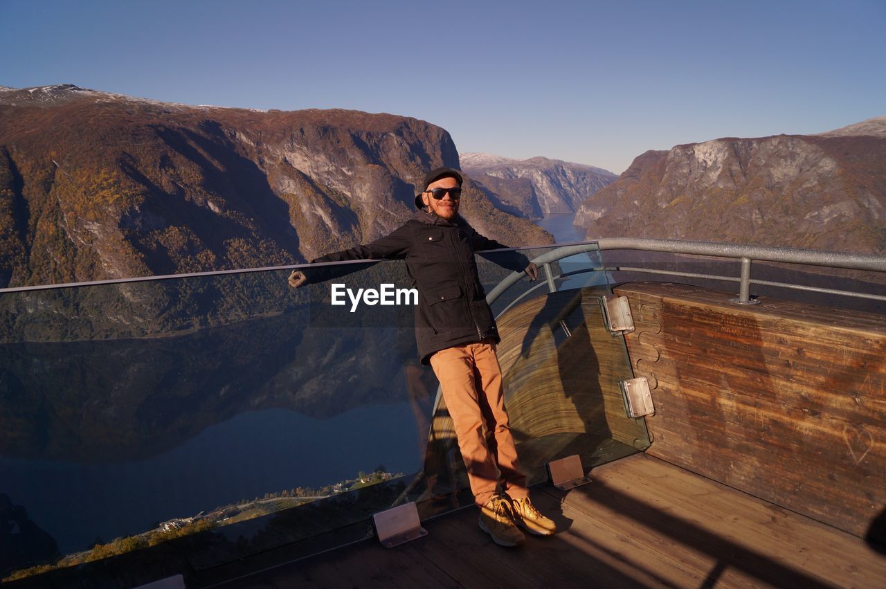 Man standing by railing against mountains