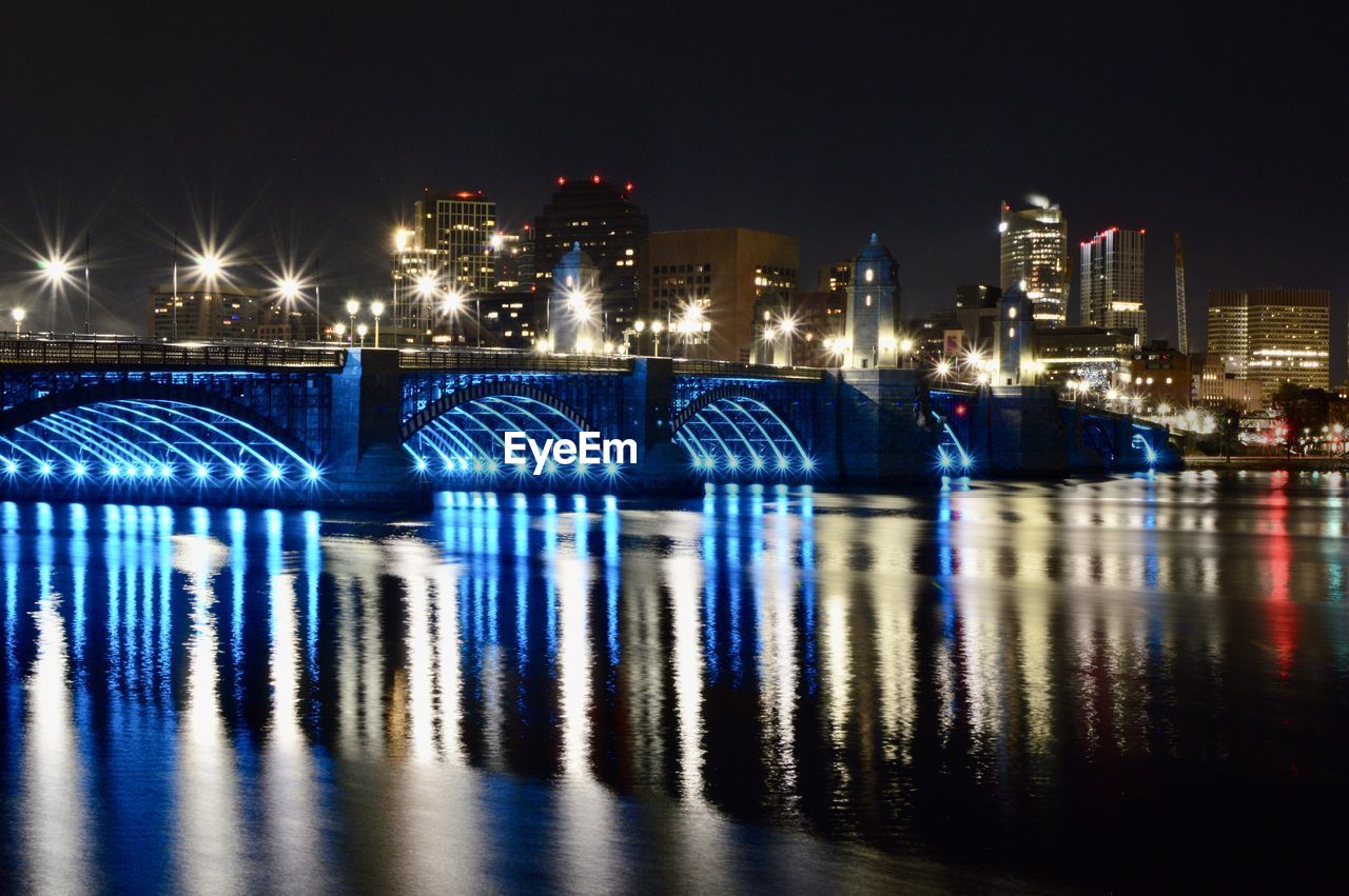 illuminated bridge over river against sky at night