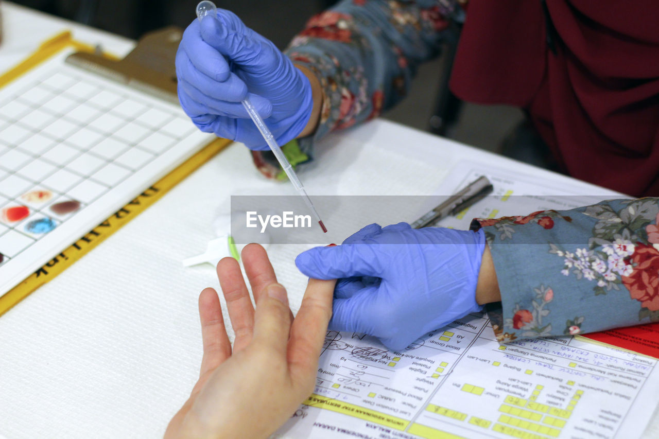 Cropped hands of doctor removing blood sample from patient finger