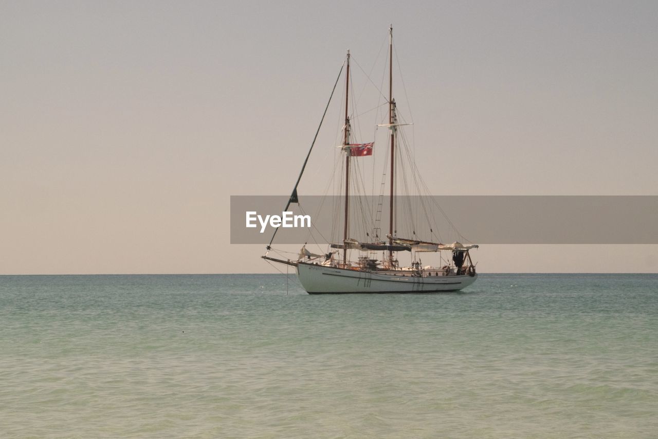 Sailboat sailing on sea against clear sky