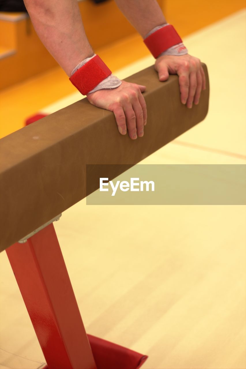 Cropped hands of person holding pommel horse in gym