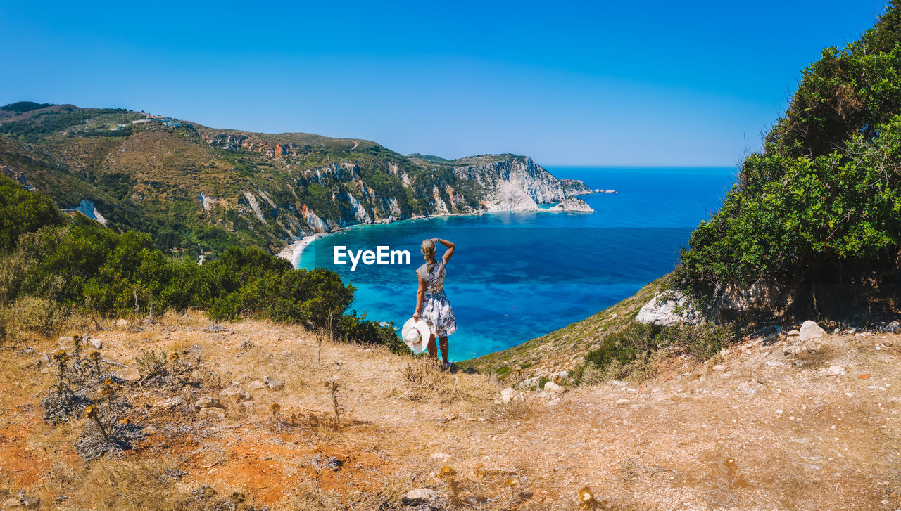 SCENIC VIEW OF SEA BY MOUNTAINS AGAINST BLUE SKY