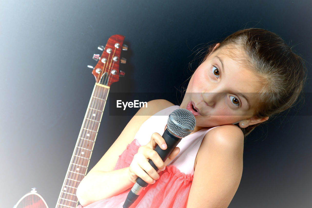 Portrait of girl singing against black background