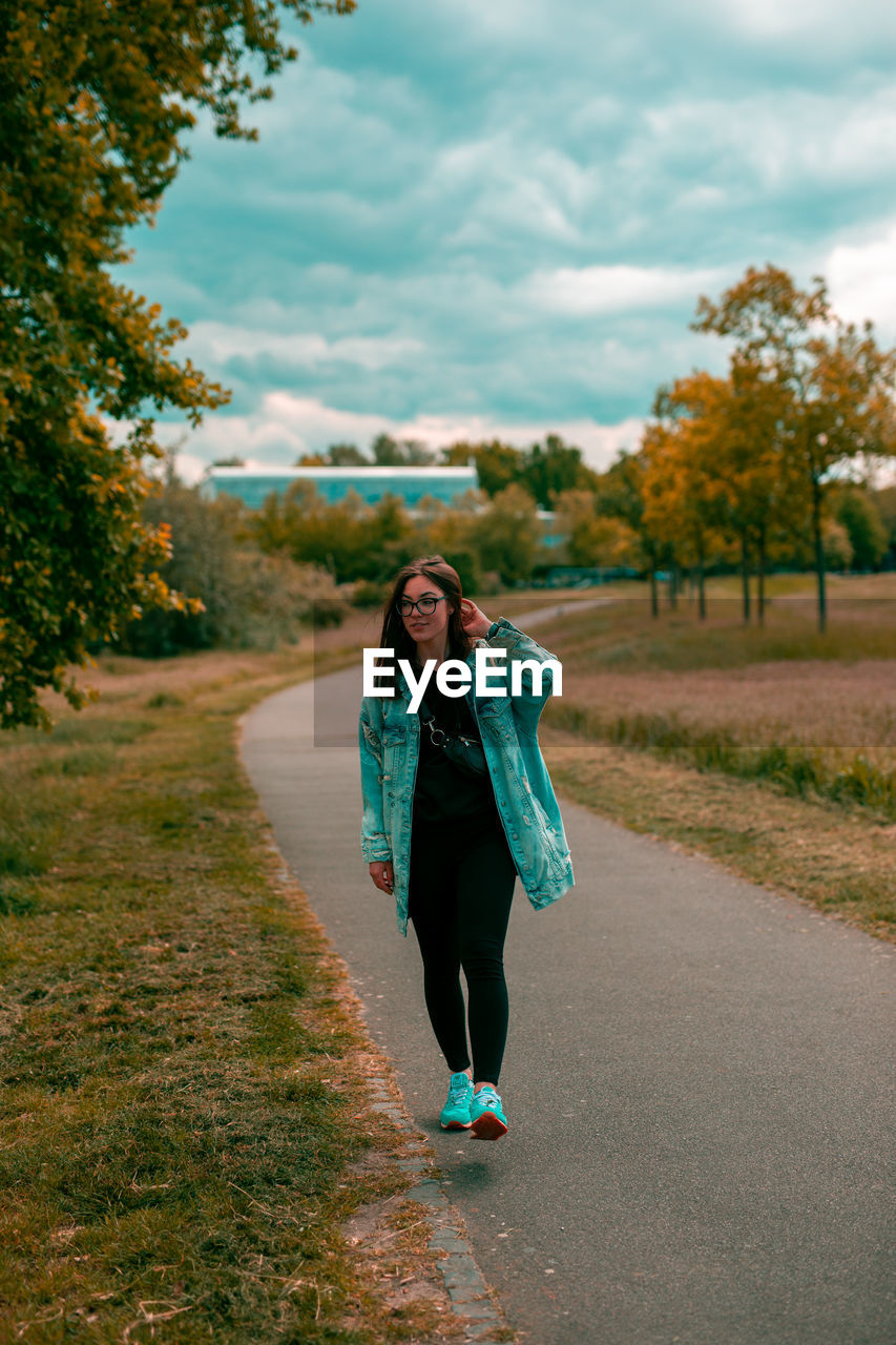 Full length of woman standing on road against sky