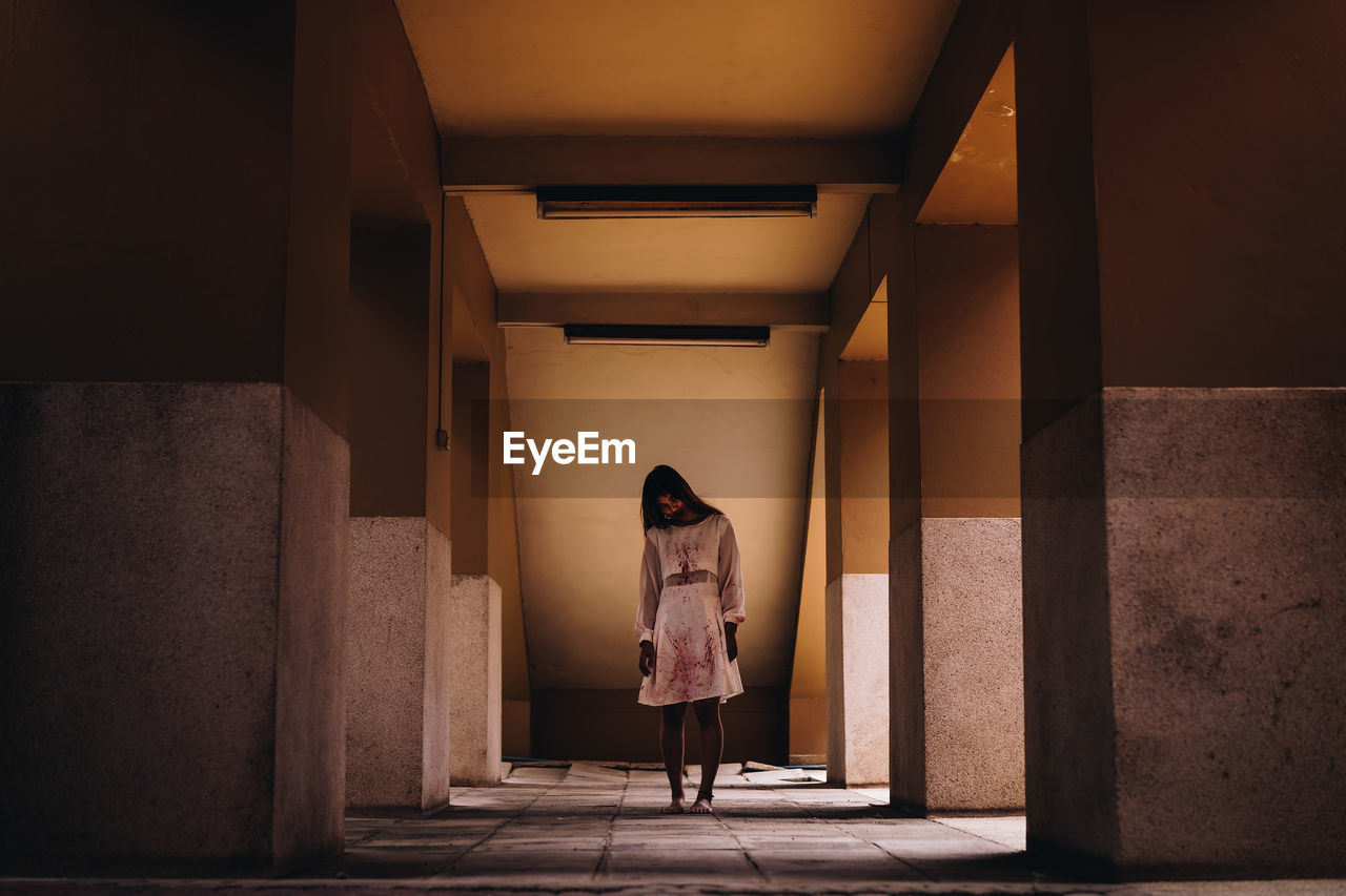 Full length of young woman with halloween make-up standing in corridor