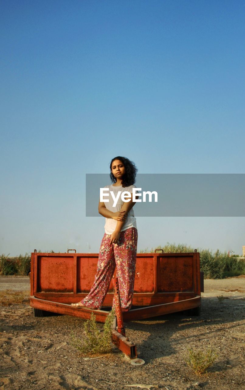 Portrait of young woman on a wagon standing next to the clear blue sky. 