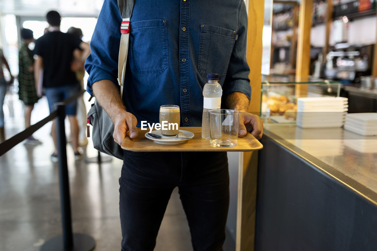 Businessman with refreshing drinks on tray in cafe