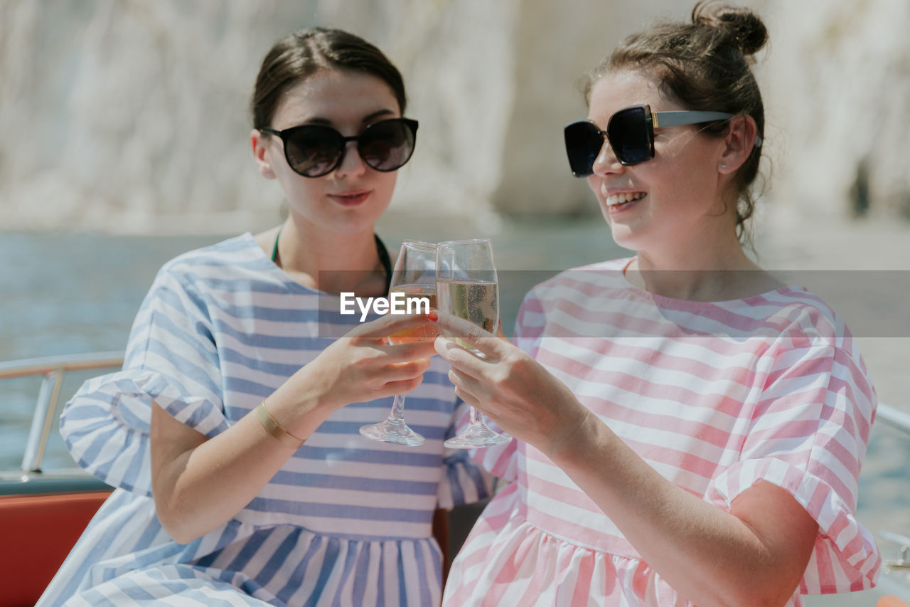 Portrait of a young couple of girls drinking champagne in a boat.