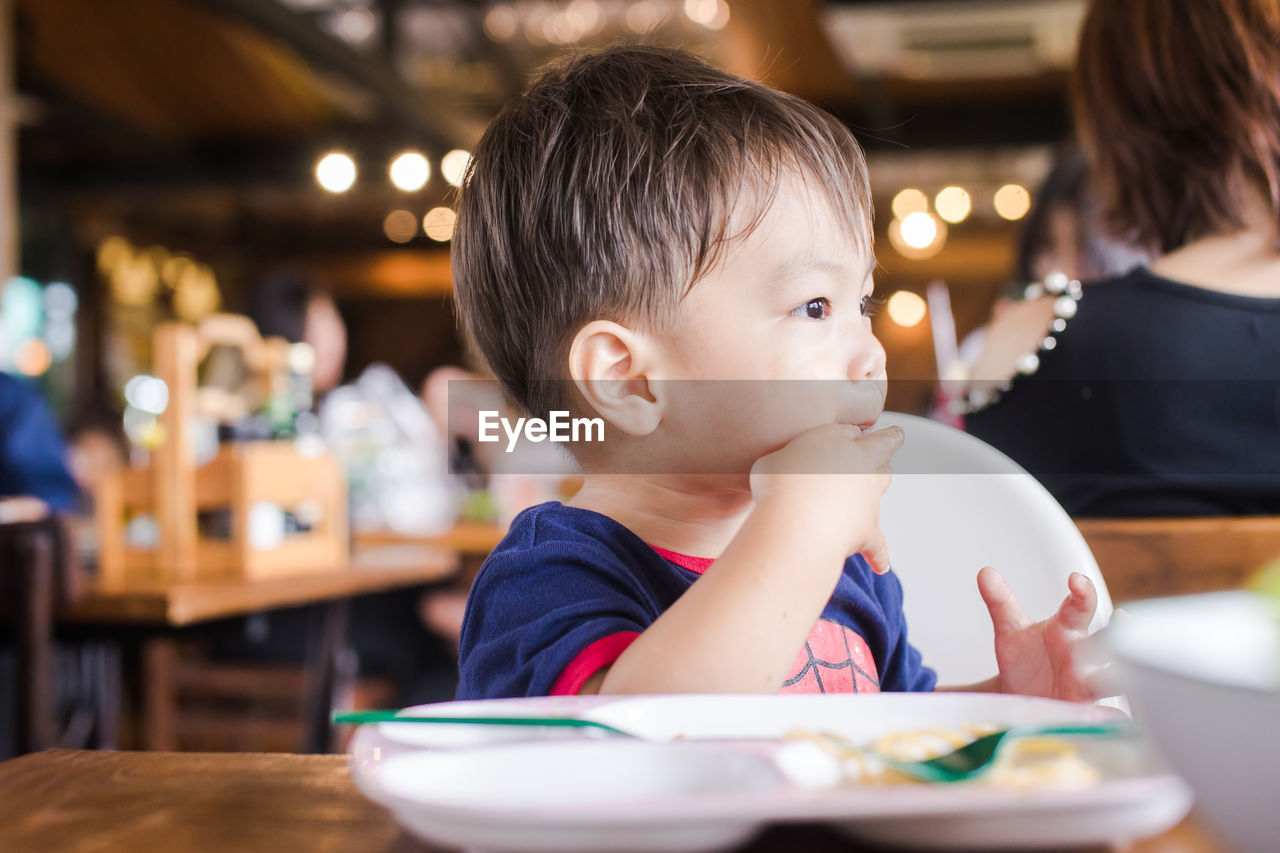 Cute baby boy having meal at restaurant