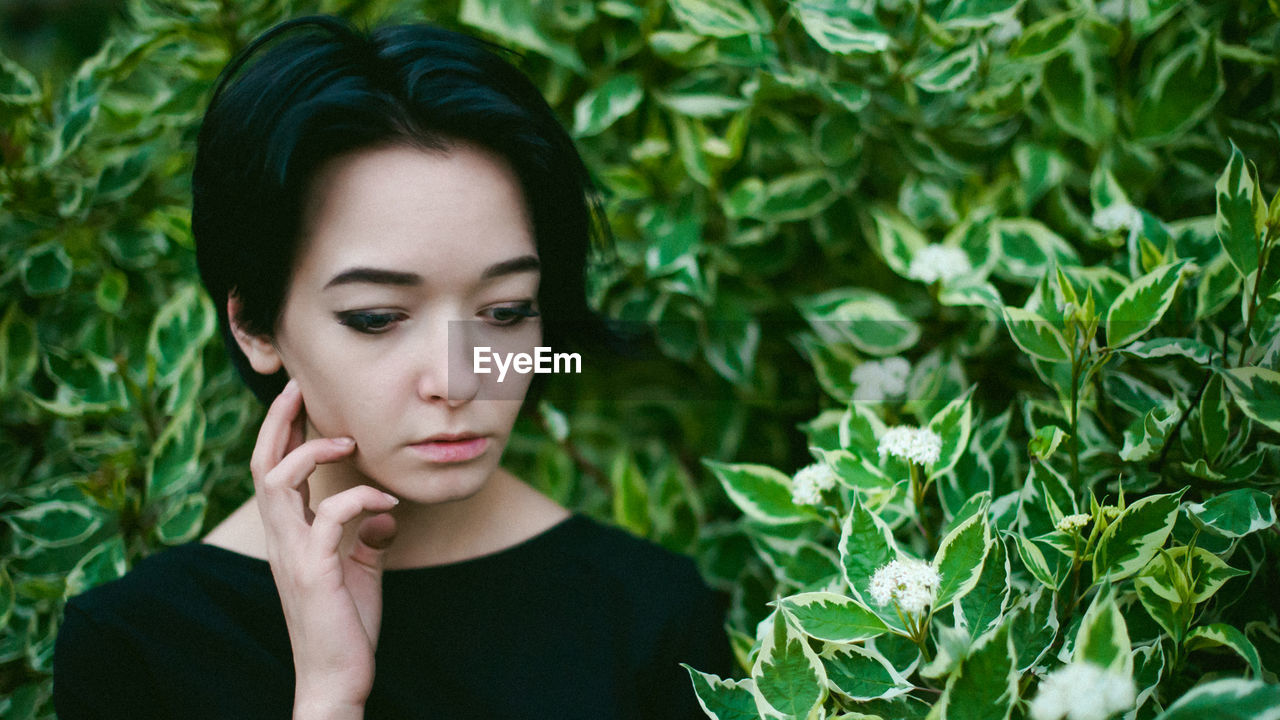 Young woman with eyes closed amidst plants