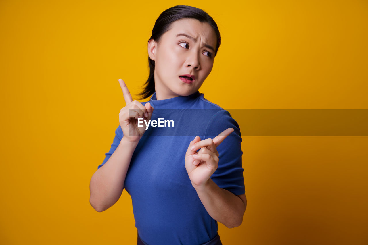 Woman standing against yellow background