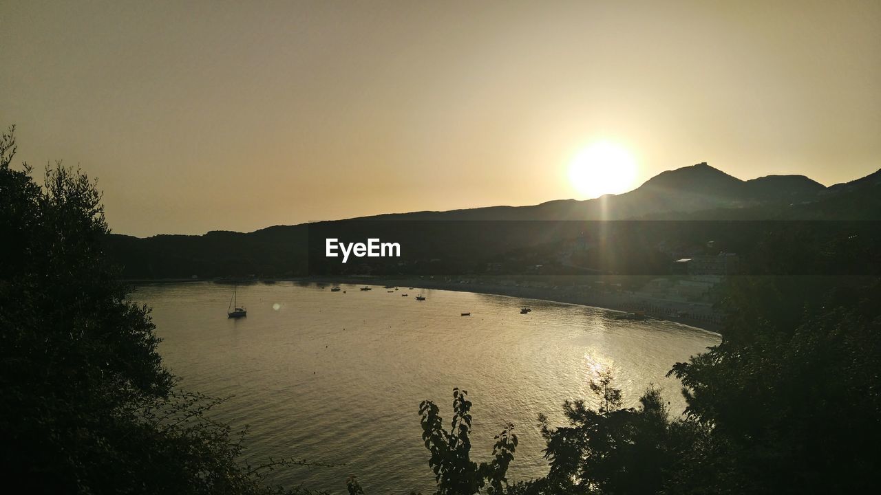 SCENIC VIEW OF MOUNTAINS AGAINST BRIGHT SUN AT SUNSET